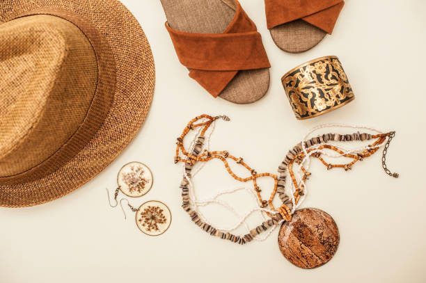 Hat, sandals, ornate bracelet, statement necklace, and earrings laid out neatly.